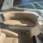 Beige cushioned bench seat near the helm of a boat, with sandals placed on the floor.