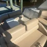 Overhead view of the boat’s seating area with beige cushions and a white table, dock visible in the background.