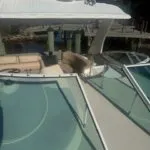 View looking down from the bow, showing windshield, canopy with Garmin radar dome, and cushioned seating area below.