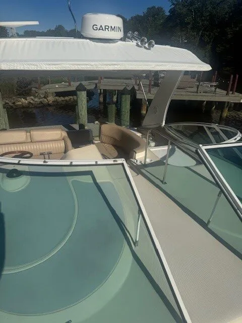 View looking down from the bow, showing windshield, canopy with Garmin radar dome, and cushioned seating area below.