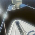 Bow of the boat showing anchor slot and a mounted device on a small platform over the water.