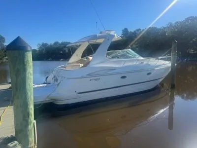 A boat docked at a calm harbour with gentle ripples on the water and surrounding piers in the background.