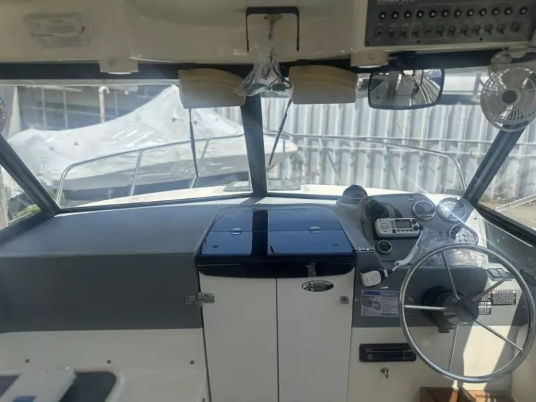 Dry cabin interior of Trophy 2359 Walkaround with cushioned seating, helm controls, and forward berth.